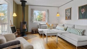 A cozy living room with a sofa, a coffee table, and a fireplace. - Authentic Swedish summer house at Asnæs plantation (Asnæs)