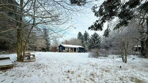 A snow-covered landscape with a house, a bench, and a tree. - Authentic Swedish summer house at Asnæs plantation (Asnæs)