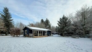 A cabin with a porch, surrounded by snow-covered trees. - Authentic Swedish summer house at Asnæs plantation (Asnæs)