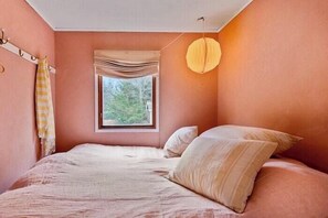 A bedroom with a bed, a window, and a hanging light fixture. - Authentic Swedish summer house at Asnæs plantation (Asnæs)