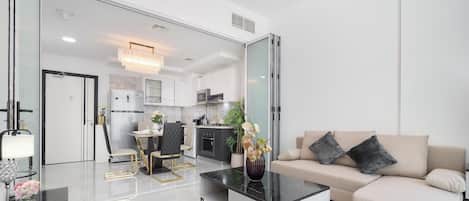 A modern living room with a sofa, coffee table, and a dining area with chairs and a table.