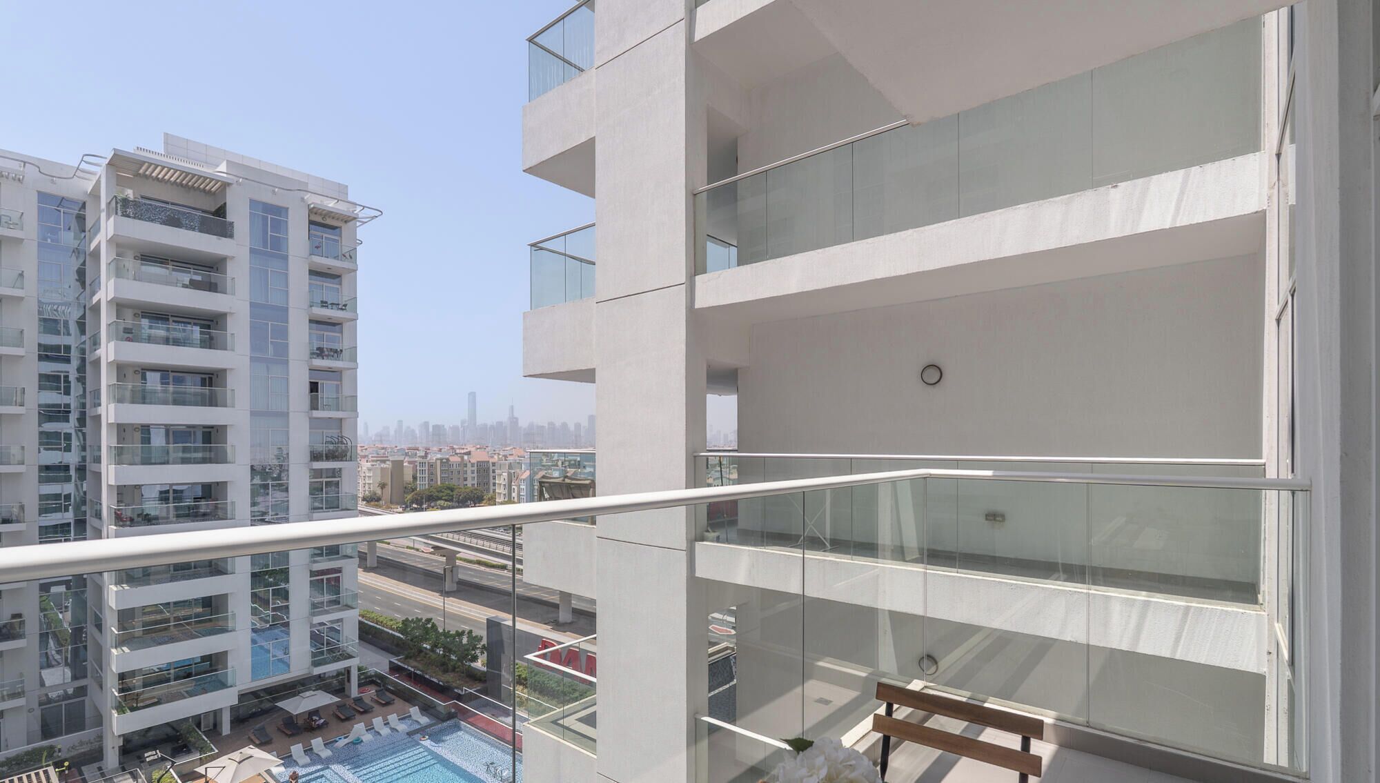 Un edificio residencial de varios pisos con balcones, piscina y vista a la ciudad.