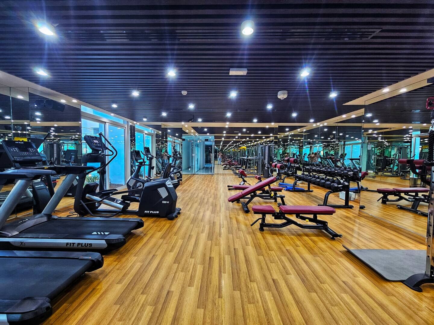 Une salle de sport équipée de tapis de course, de vélos elliptiques, de bancs de musculation et de poids libres.