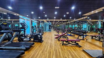 Une salle de sport équipée de tapis de course, de vélos elliptiques, de bancs de musculation et de poids libres.