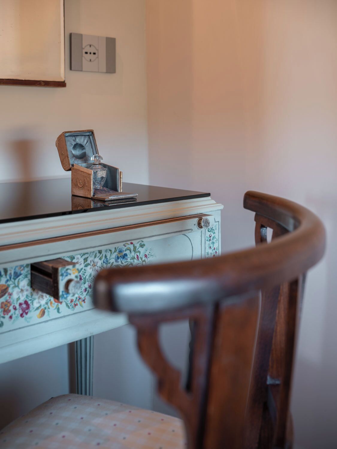 A wooden chair with a floral-patterned table in front of it.