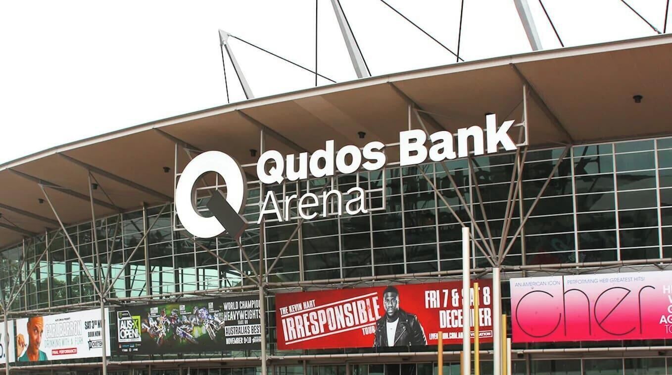 Un edificio grande con un letrero llamativo para Qudos Bank Arena.