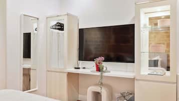 Un dormitorio con cama, escritorio con ordenador, televisor y armario.