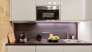 Eine Küche mit Edelstahlbackofen, Wasserkocher, Obstschale und Spüle.