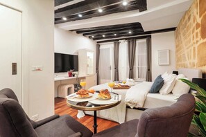 A modern hotel room with a bed, a dining table with breakfast, and a TV. - Cozy Studio in the Heart of Paris - Louvre (Paris)