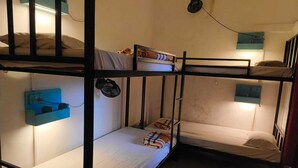 A bunk bed room with a small desk and a wall-mounted fan. - Mitra Hostel (Arambol)