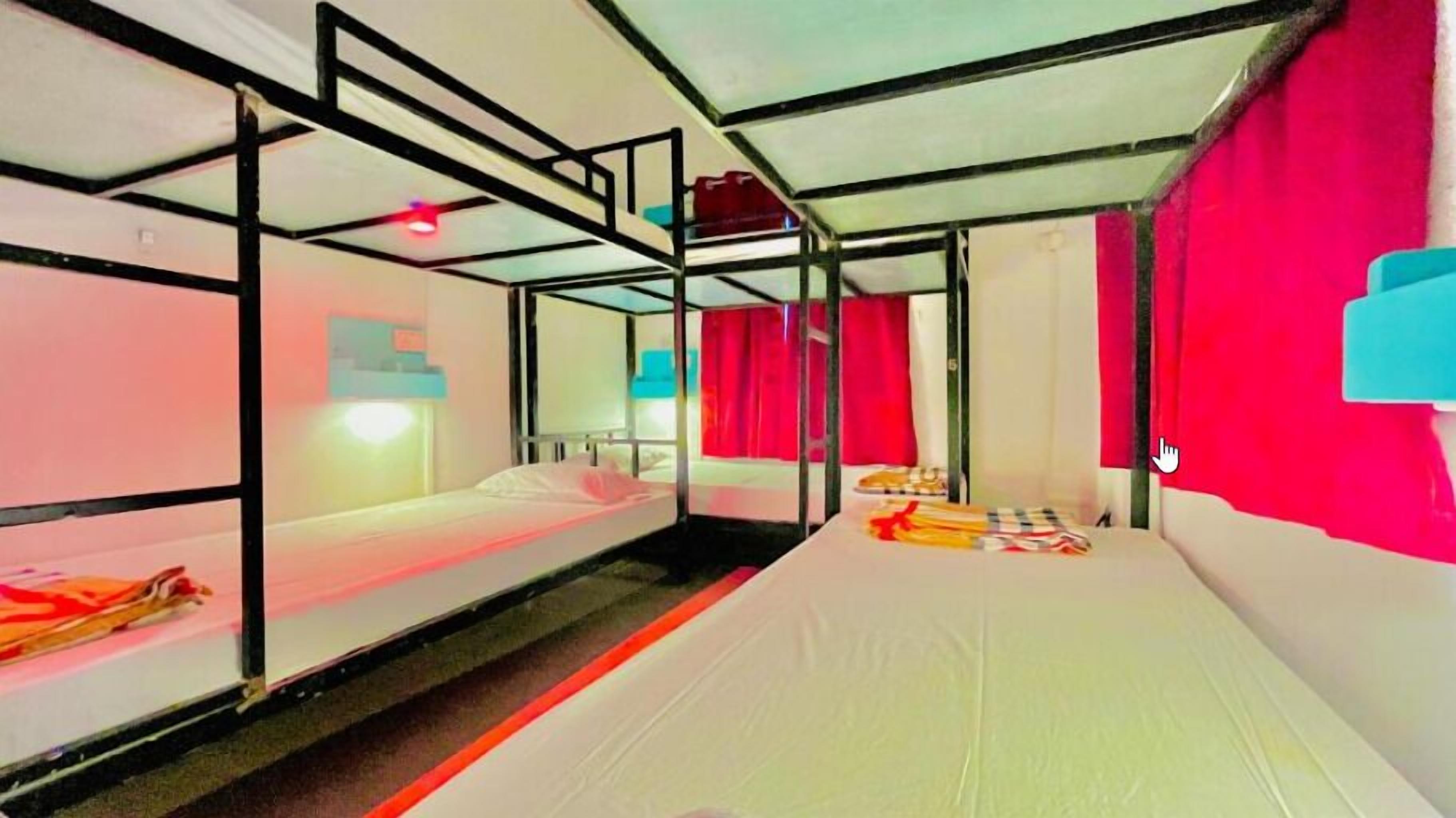 Une chambre avec un lit superposé, un rideau rouge, un matelas blanc et une structure en métal.