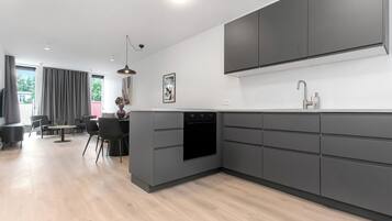 Una cocina moderna con armarios grises, un horno empotrado y una zona de comedor con mesa y sillas.