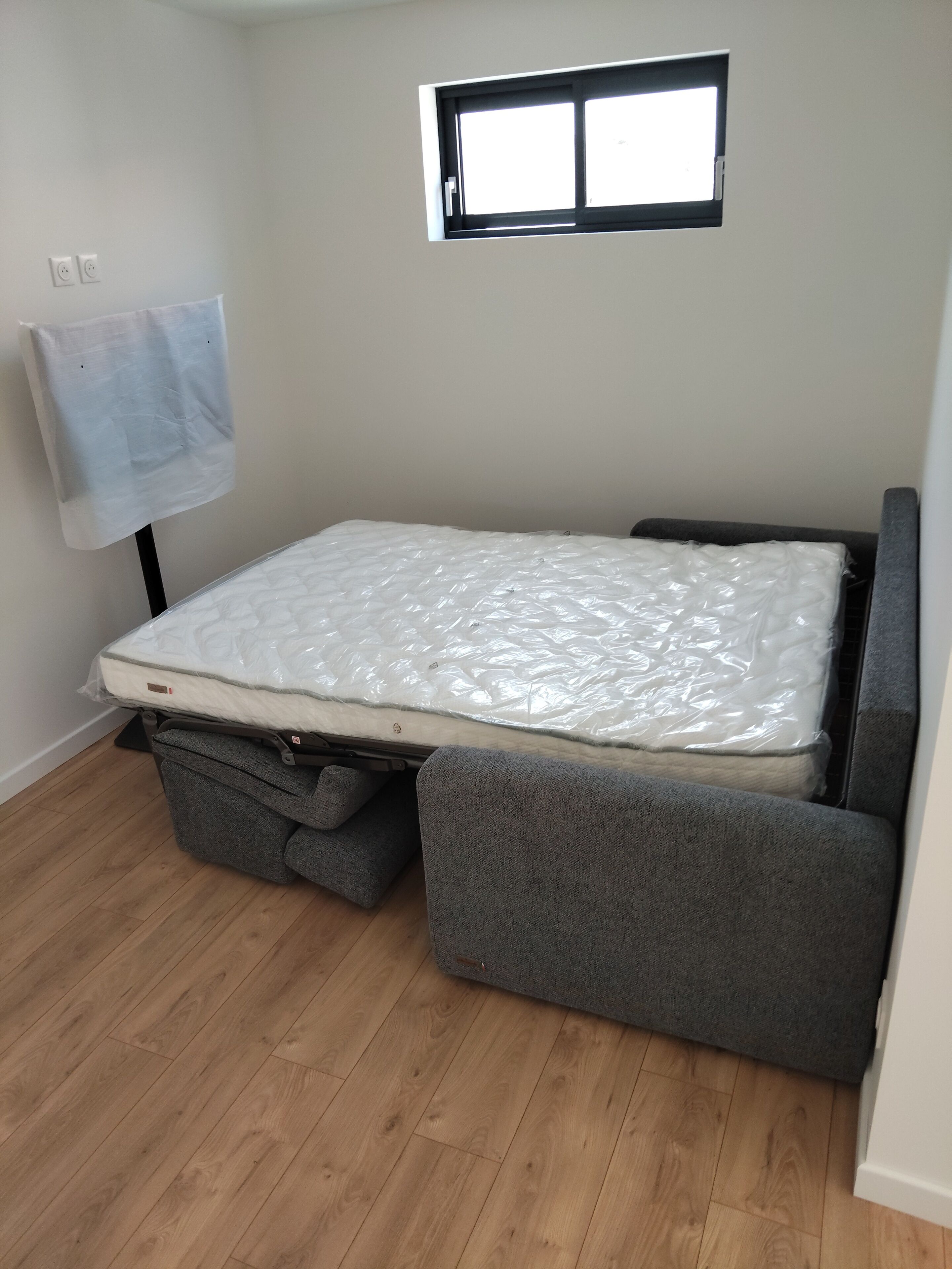 Une pièce avec un lit, une fenêtre et une serviette accrochée au mur.
