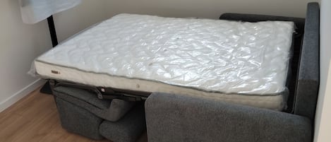 A room with a bed, a window, and a towel hanging on the wall.