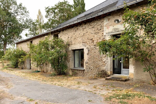 A rustic stone building with a sloped roof, a front door, and a window.