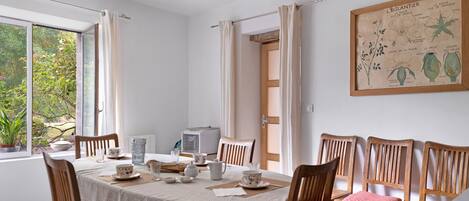 Un coin repas avec une table ronde, des chaises et une radio d’époque.