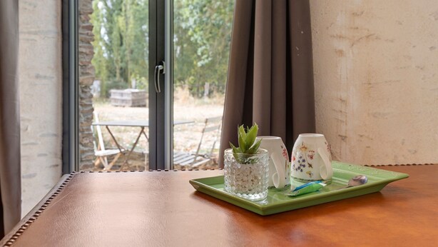 A table with a green tray holding a glass container with white beads, a white mug with floral designs, and a spoon. - "Chambre Terrasse" Guest Room with Shared Terrace, Garden, and Wi-Fi (La Possonnière)