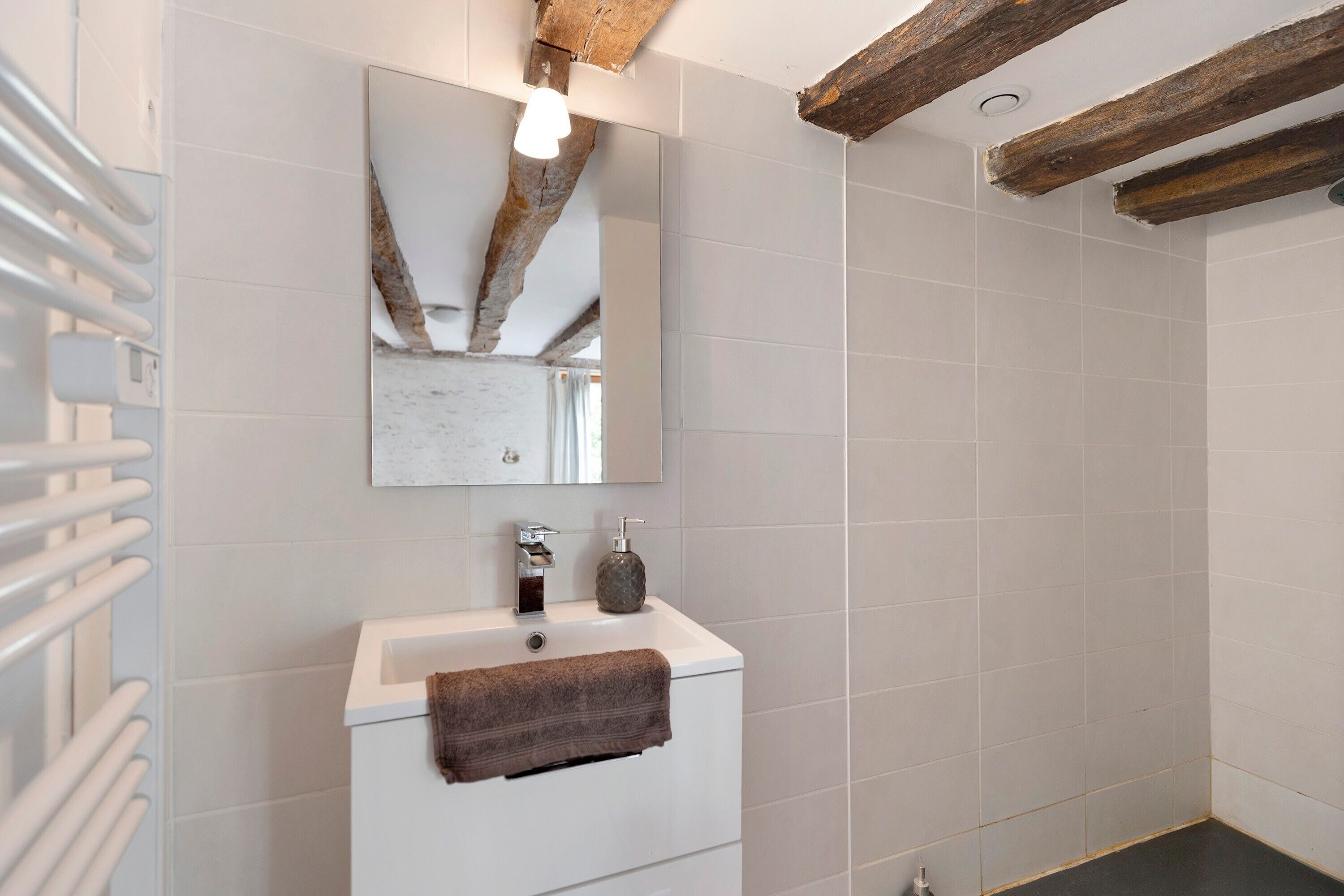 Een badkamer met een witte wastafel, een spiegel, een handdoek en een douche.