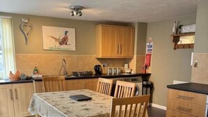 Una cocina con armarios de madera, una mesa de comedor con sillas, un banco y piso de baldosas.