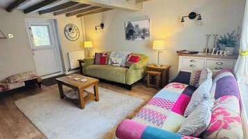 A cozy living room with a wooden floor, a sofa, a coffee table, and a lamp.