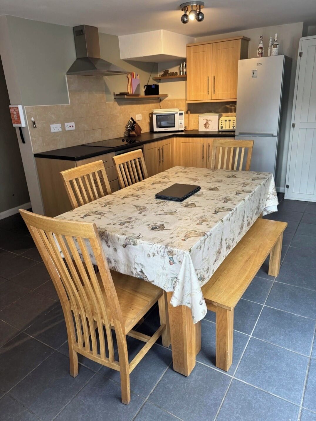 A dining area with a table set for four, surrounded by wooden chairs.