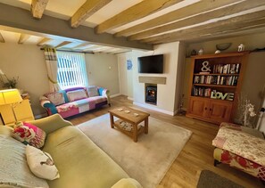 Una sala de estar acogedora con sofá, mesa de centro, chimenea, televisor y estantería.