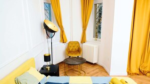 Una habitación con cama, una silla, una mesa, una lámpara y cortinas.