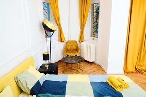 A room with a bed, a chair, a table, a lamp, and curtains. - Refined Central Sanctuary – Perfect Romantic Getaway by the River – 701 (Budapest)