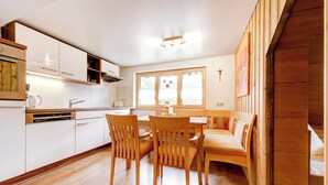 A modern kitchen with white cabinets, a wooden dining table, and chairs. - Schwendehof Vacation Home, Rental Unit 1 (Fontanella)