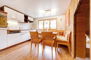 A modern kitchen with white cabinets, a wooden dining table, and chairs. - Schwendehof Vacation Home, Rental Unit 1 (Fontanella)