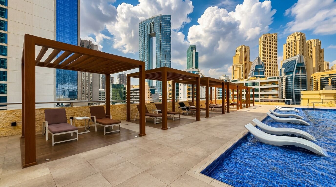 A rooftop pool area with lounge chairs and a view of city skyscrapers.