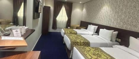 A hotel room with two beds, a desk, a mirror, and a patterned wall.