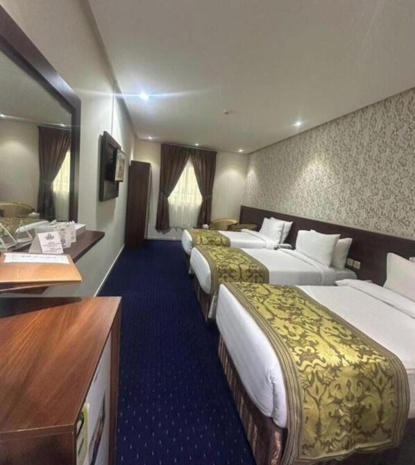 A hotel room with two beds, a desk, a mirror, and a patterned wall. - Maysan Al Safa Hotel (Makkah)