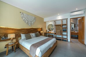 A modern bedroom with a wooden headboard, a large bed, a bedside table with a lamp, a wall-mounted macrame piece, a wooden desk with a chair, a mirror, and a wardrobe. - Villa Yuka (Ubud)