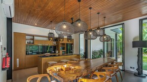 A modern kitchen with wooden cabinets, a central island, and pendant lighting. - Villa Yuka (Ubud)