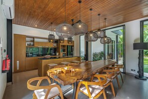A modern kitchen with wooden cabinets, a central island, and pendant lighting. - Villa Yuka (Ubud)