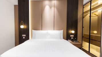 A hotel room with a large bed, bedside lamps, a nightstand, and a wardrobe with a mirror.