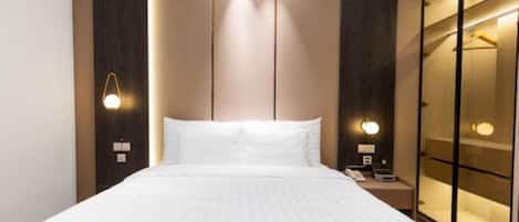 A hotel room with a large bed, bedside lamps, a nightstand, and a wardrobe with a mirror.