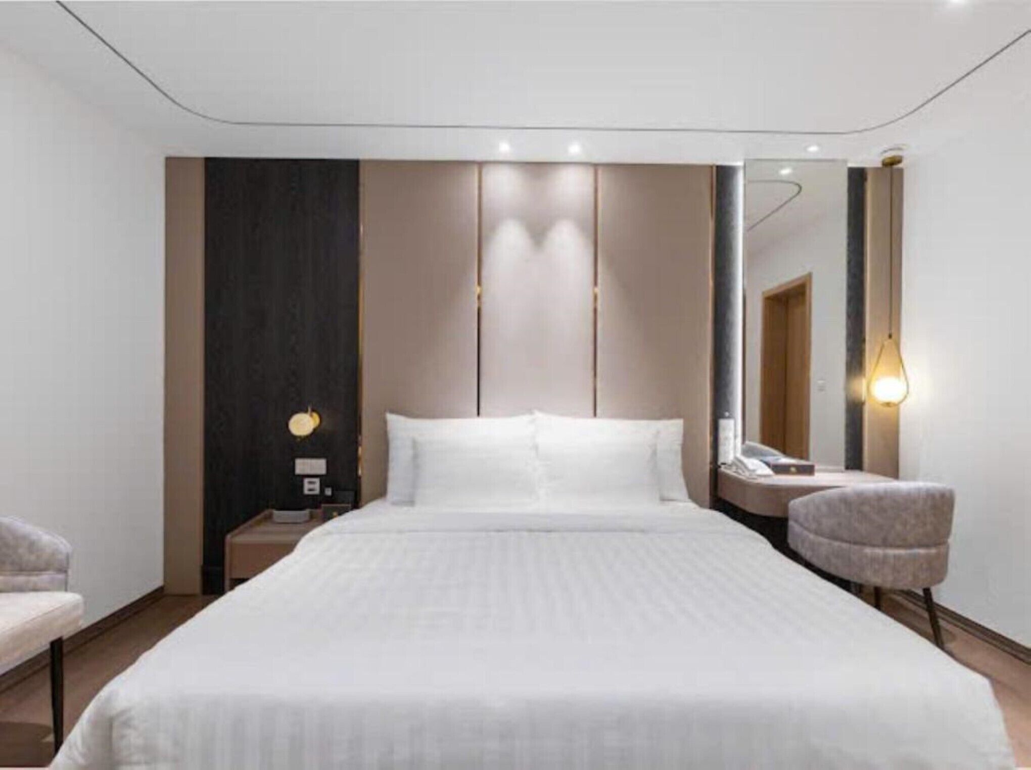 Una habitación de hotel moderna con una cama grande, una mesita de noche, una silla y un espejo.