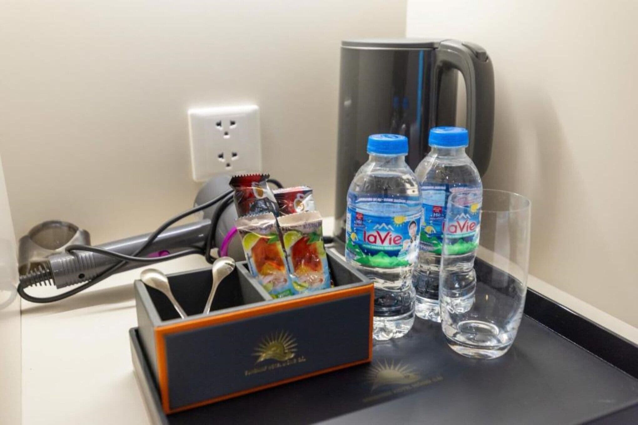 A hotel minibar with a beverage dispenser, a glass, and a juice carton.
