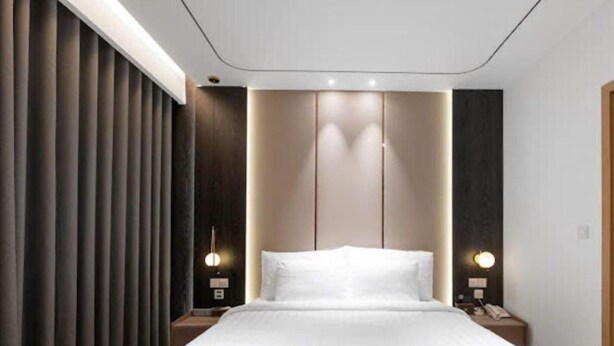 A modern hotel room with a large bed, dark wood paneling, and two bedside lamps. - Sunshine Grand Hotel (Mong Cai 2)