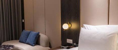 A hotel room with a bed, a sofa, and a nightstand with a lamp.