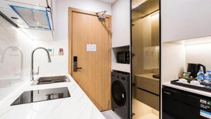A compact kitchen with a sink, a washing machine, and a microwave. - Sunshine Grand Hotel (Mong Cai 2)