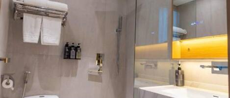 Ein modernes Badezimmer mit Duschkabine aus Glas, Toilette, Waschbecken mit gelber Arbeitsplatte und Spiegel.