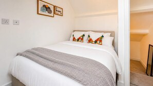 Une chambre à coucher comprenant un lit, une tête de lit, une lampe fixée au mur et une porte donnant sur une autre pièce.
