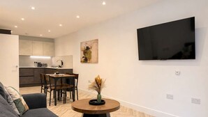 A modern living room with a sofa, a dining table, and a kitchen in the background. - Modern 1BR - Sleeps 4 - Free Parking - Manchester (Manchester)