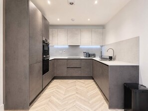A modern kitchen with built-in appliances, a herringbone-patterned floor, and a minimalist design. - Modern 1BR - Sleeps 4 - Free Parking - Manchester (Manchester)