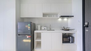Cocina compacta con refrigerador, microondas, tetera y estufa.