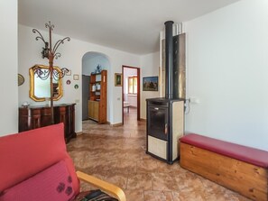 Ein Wohnzimmer mit Kamin, einem roten Sofa, einer Holzbank und einem Flur, der in einen anderen Raum führt.