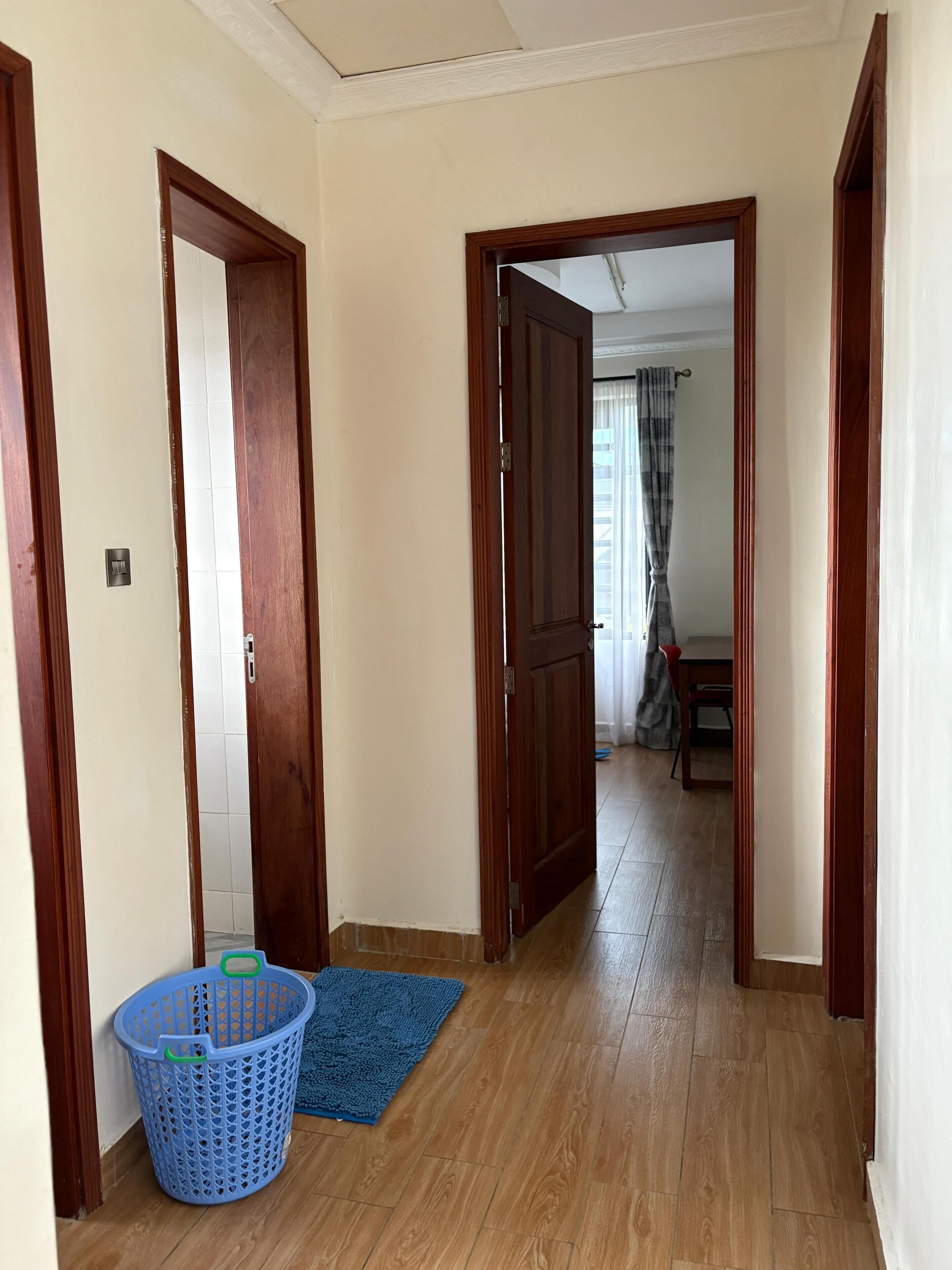 A hallway with wooden doors, a blue mat, and a blue basket.